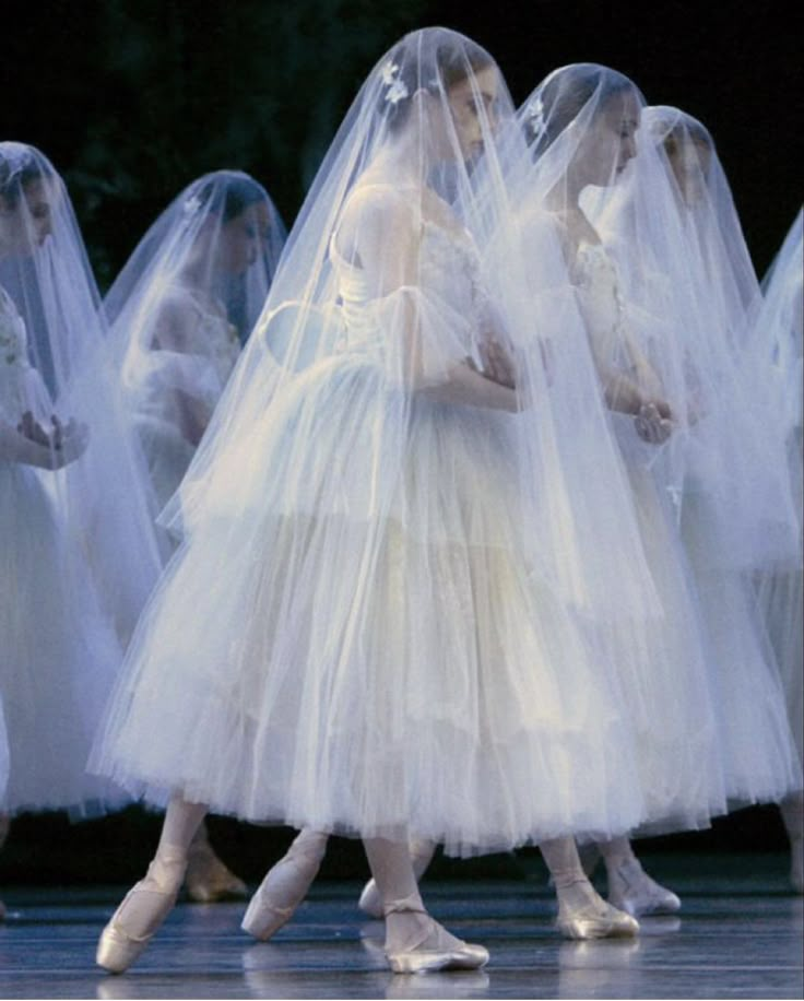 several ballerinas in white tulle dresses and veils are walking on stage