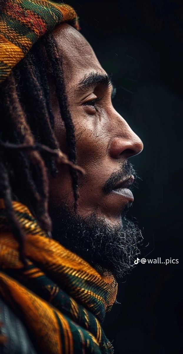 a man with dreadlocks and a scarf around his neck looking off into the distance