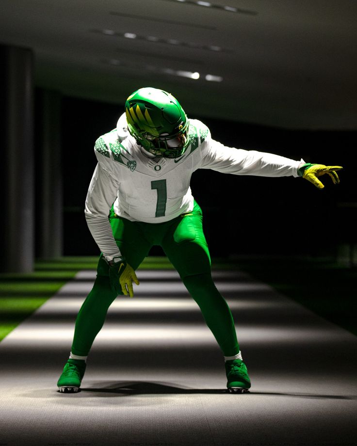 a man in green and white football uniform standing on one foot with his arms outstretched