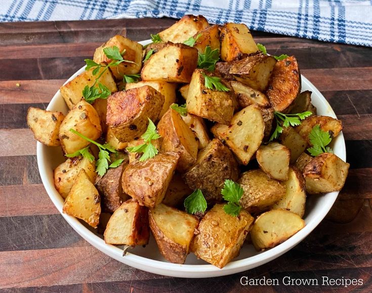 a white bowl filled with cooked potatoes on top of a wooden table