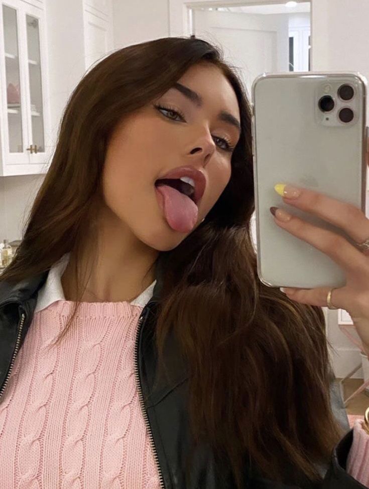 a woman sticking her tongue out while taking a selfie in front of a mirror