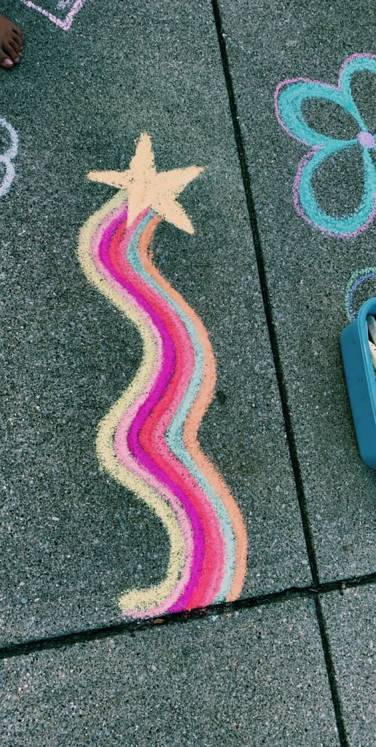 a child's chalk drawing on the ground with crayons and scissors next to it