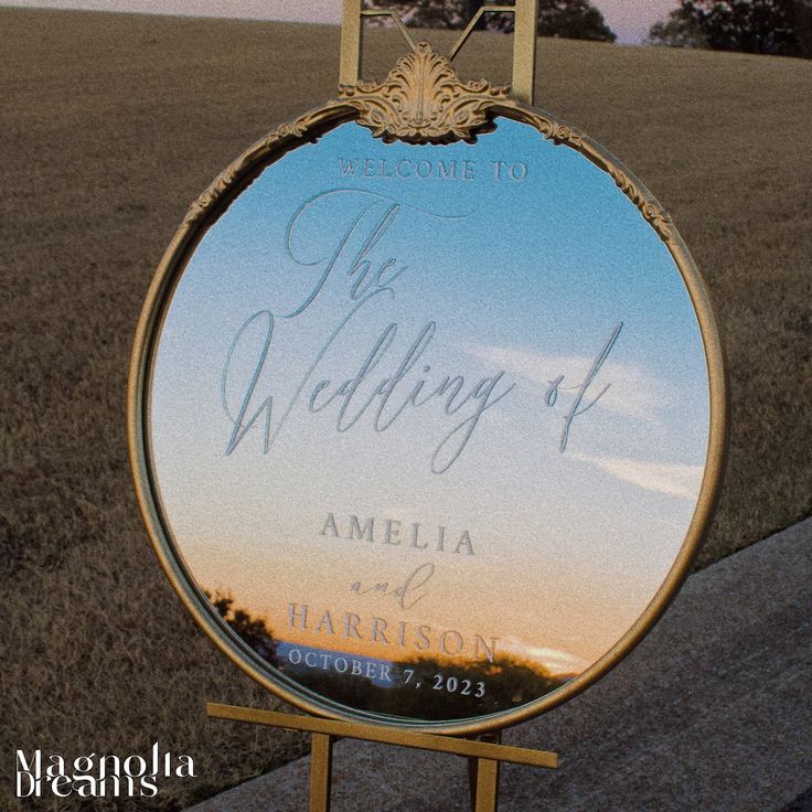 a wedding sign in front of a mirror on the side of a road at sunset