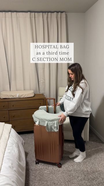 a woman standing next to a brown suitcase in a room with white walls and curtains