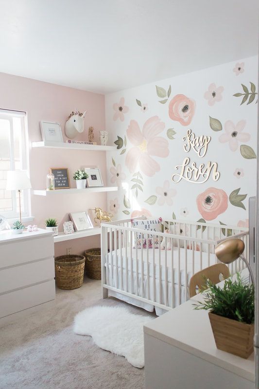 a baby's room with pink and white flowers on the wall