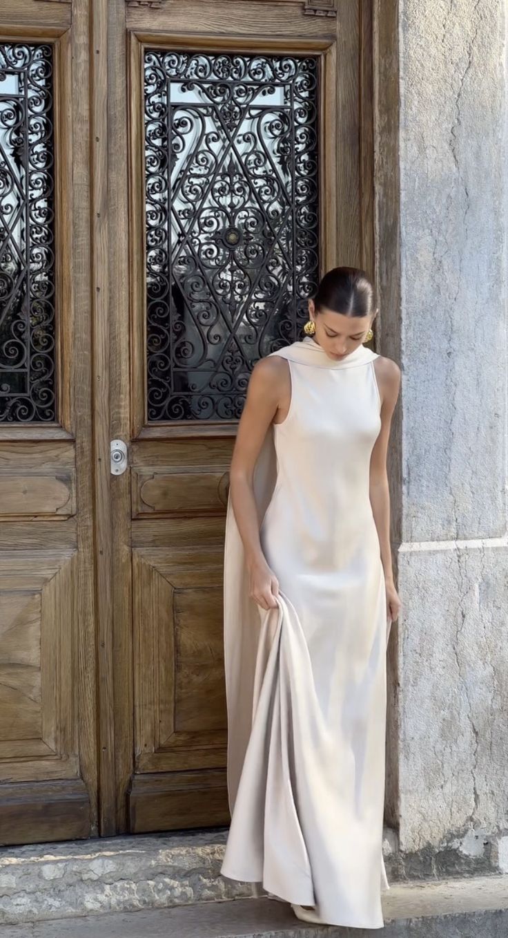 a woman standing in front of a wooden door wearing a white dress and matching heels