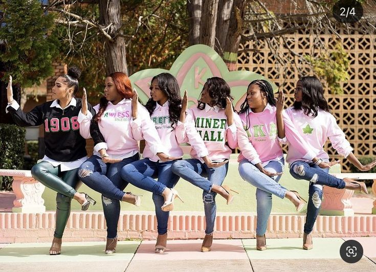 a group of young women sitting next to each other on top of a cement slab