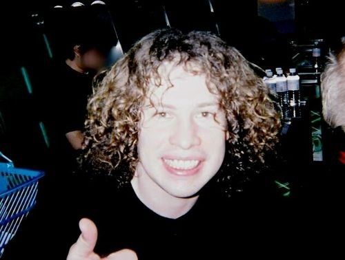 a man with curly hair giving the thumbs up