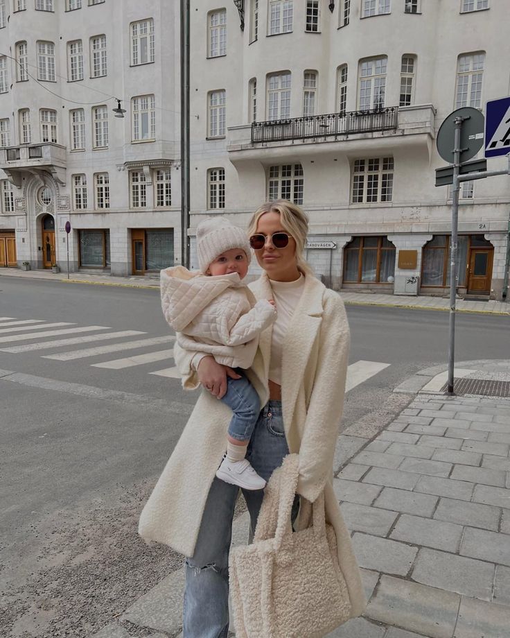 a woman holding a baby in her arms while standing on the side of a road