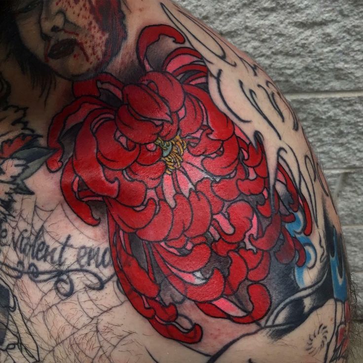 a man with tattoos on his chest has a red flower tattoo on his left shoulder