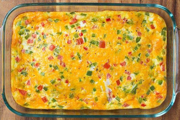 a casserole dish with cheese and vegetables in it on a wooden table top