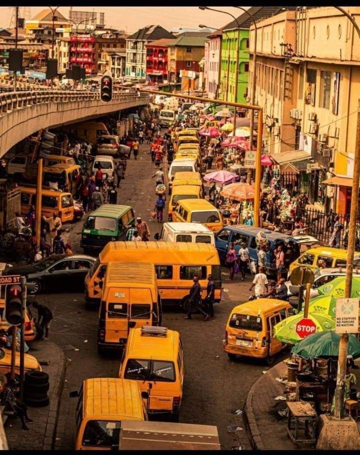 a busy city street filled with lots of traffic and people walking on the side walk