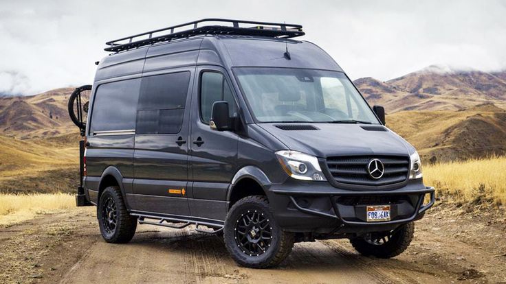 a mercedes van parked on a dirt road with mountains in the background