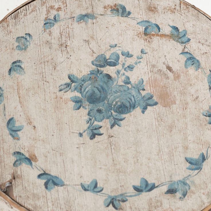 an old wooden table with blue flowers painted on it