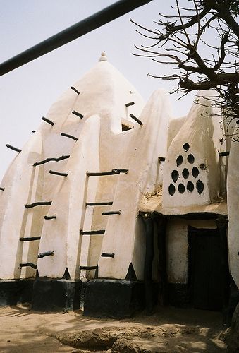 an old building made out of white clay with black holes in the front and side