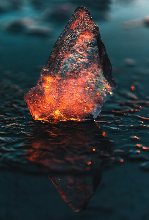 a rock that is in the water with some light coming from it's side