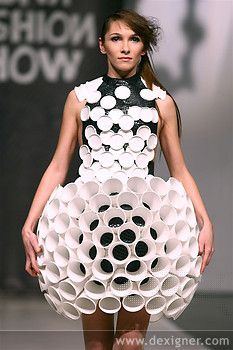 a woman is walking down the runway in a dress made out of cups