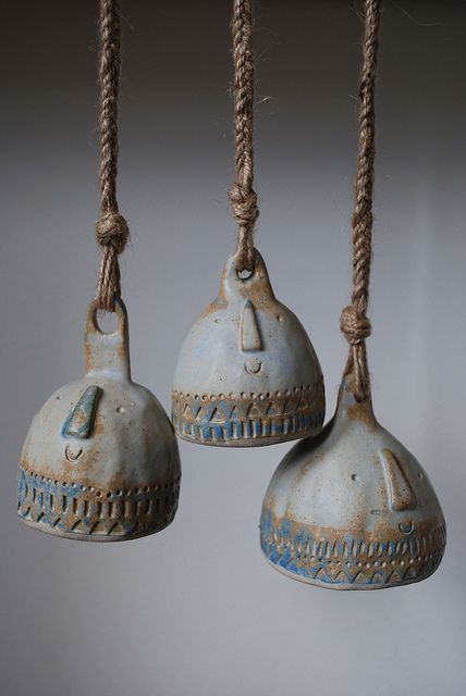 three bells hanging from ropes in the air with no strings attached to them, one is blue and the other has white paint on it