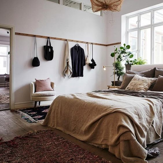 a bed sitting in a bedroom next to a window with potted plants on it