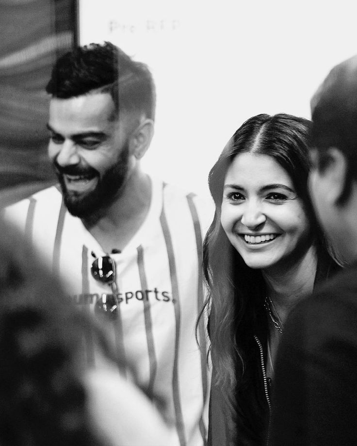 black and white photograph of two people smiling at the same person in front of them