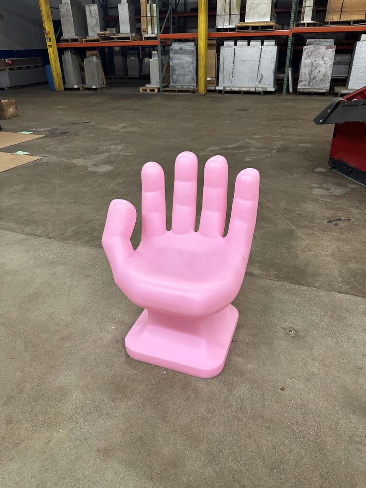 a pink hand shaped chair in a warehouse