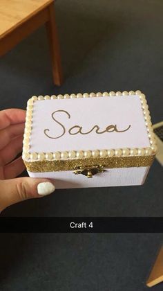 someone is holding up a small box with pearls on the edges and writing saa