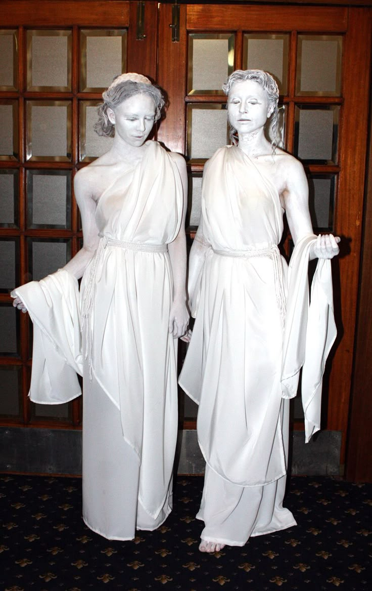 two statues of women dressed in white standing next to each other