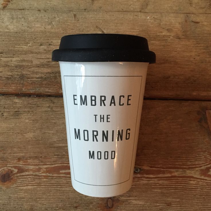 a coffee cup with the words embrace the morning mood on it sitting against a wooden wall