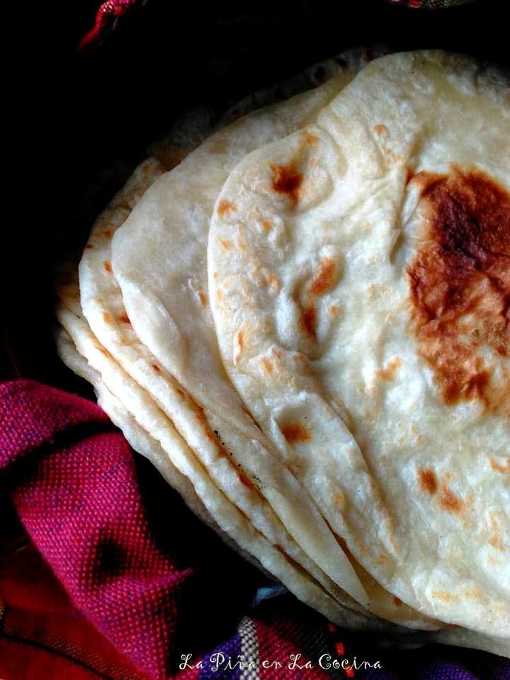 several tortillas stacked on top of each other in a bowl with red cloth