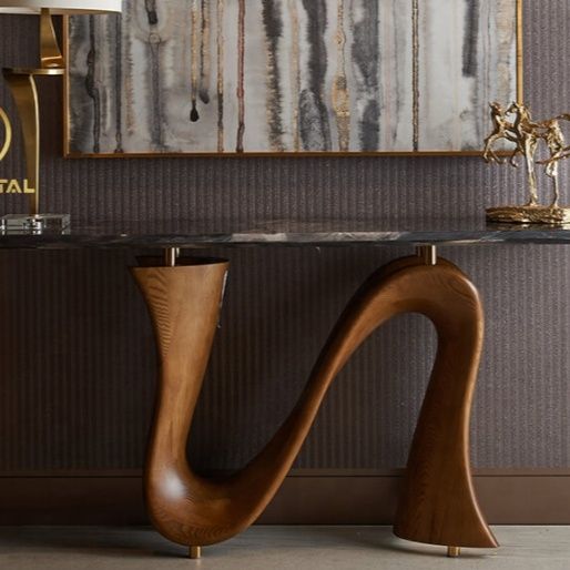 a modern console table with marble top and curved legs in front of a painting on the wall