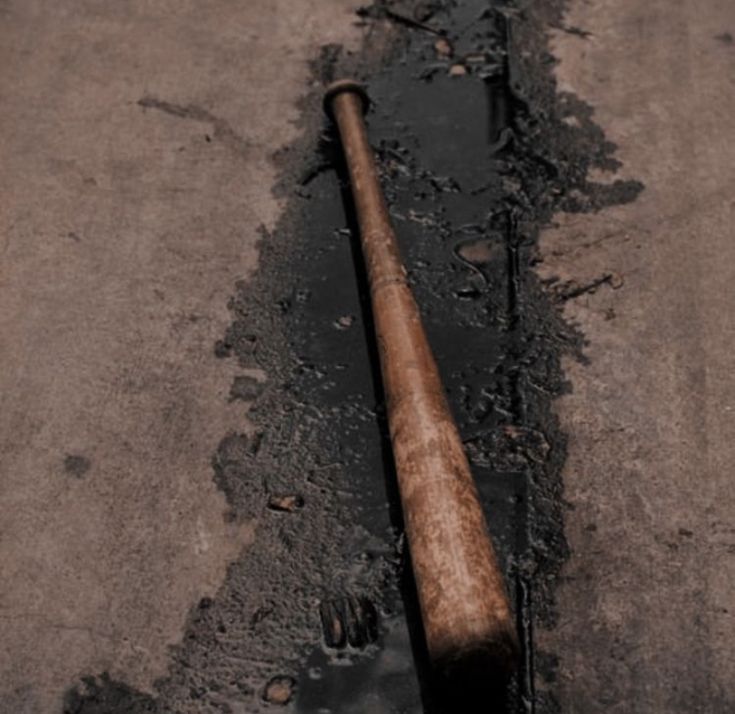 an old baseball bat laying on the ground next to a hole in the road that has been dug up