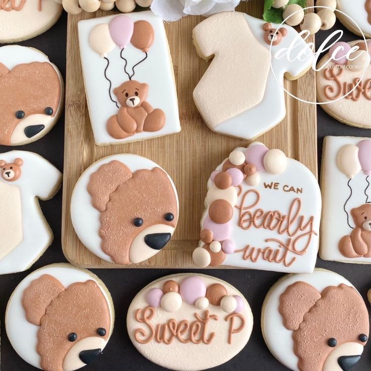 decorated cookies with teddy bears and balloons are arranged on a cutting board