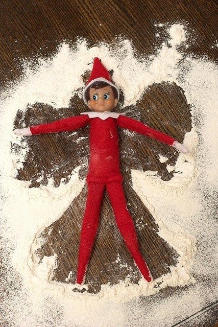 an elf doll laying on top of some white powdered sugar next to a pile of flour