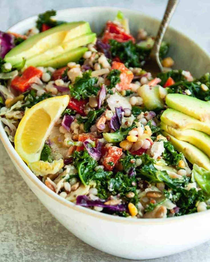 a white bowl filled with salad and sliced up avocados on top of it