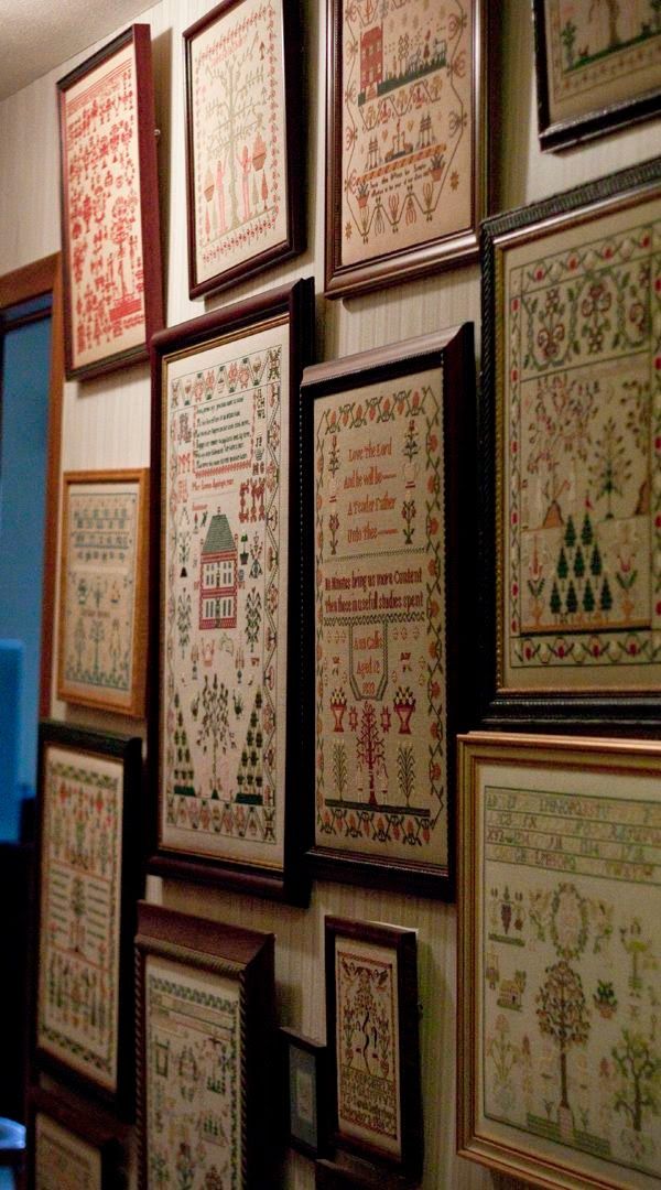 many framed cross - stitchs are hung on the wall