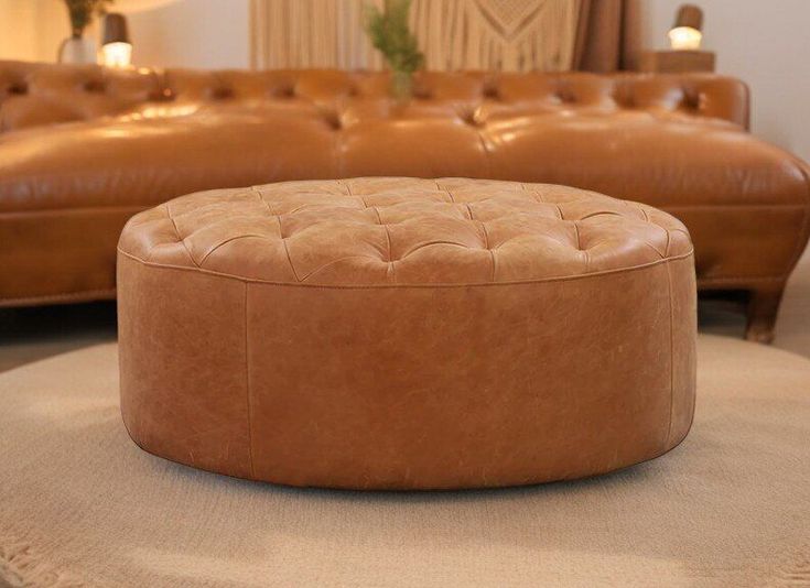 a tan leather ottoman sitting on top of a rug in front of a brown couch