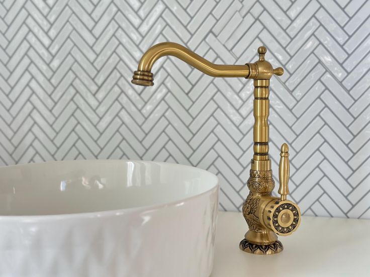 a golden faucet sitting next to a white bowl on top of a counter