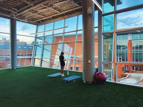 a woman standing on top of a green field next to a gym ball and exercise equipment