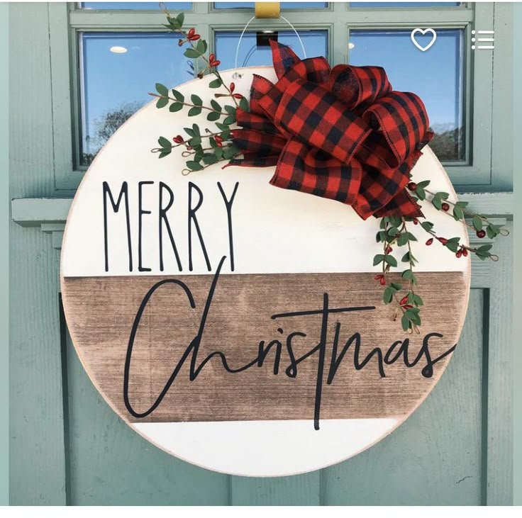 a merry christmas sign hanging on a door with red and black plaid bow around it