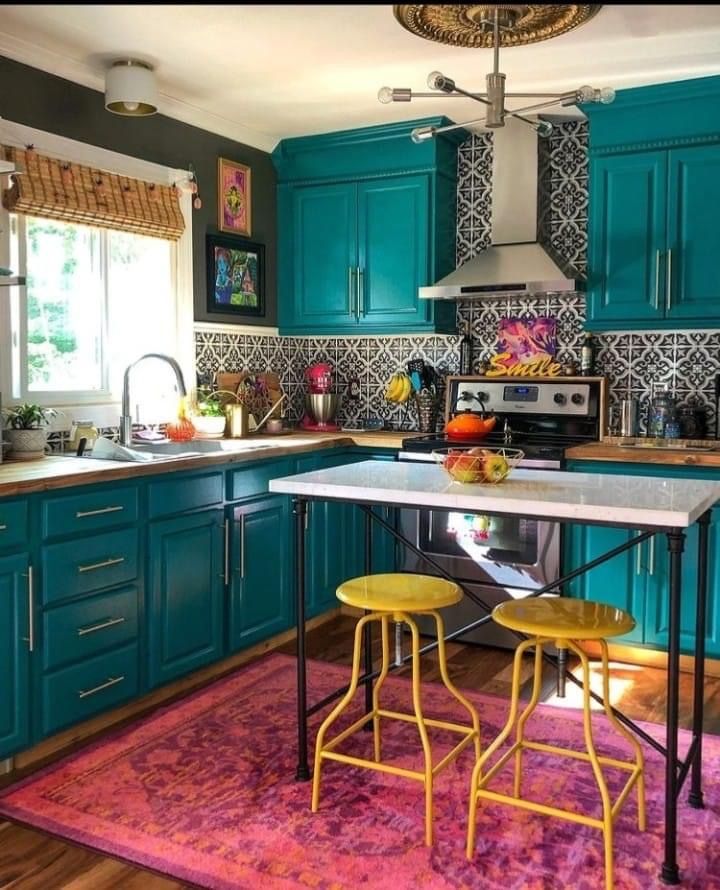 a kitchen with teal cabinets and yellow stools in front of the counter top