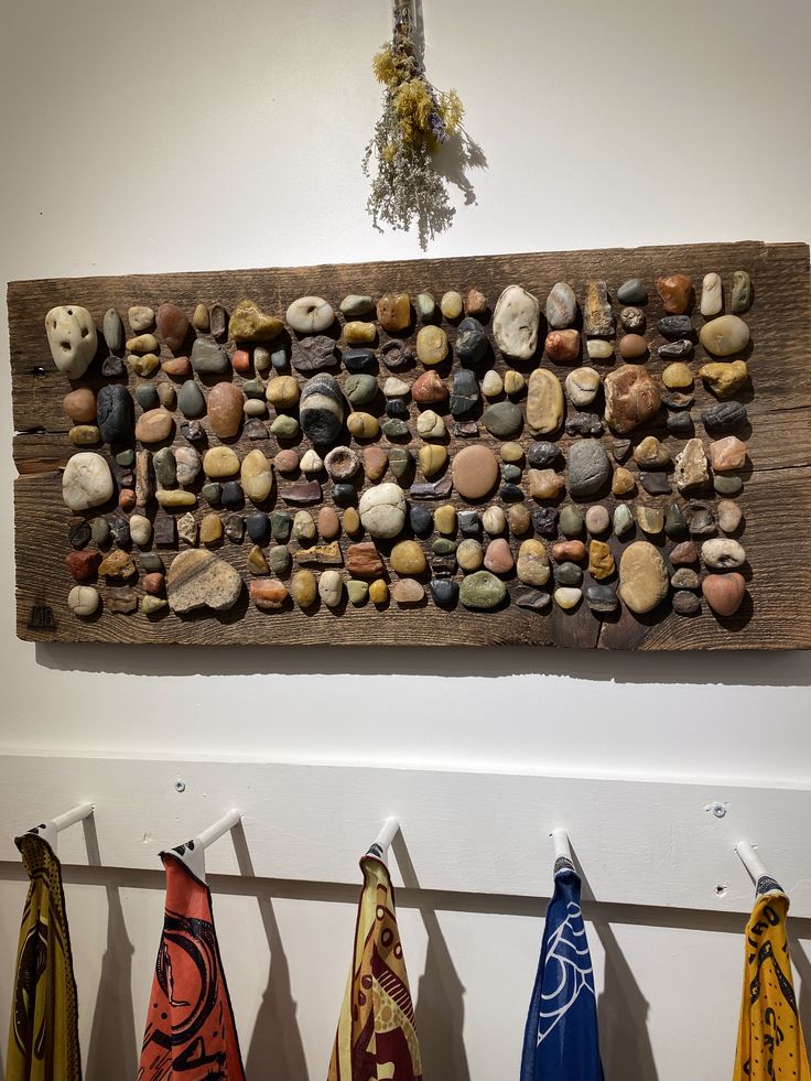 several towels are hanging on the wall next to a sign with rocks and stones in it