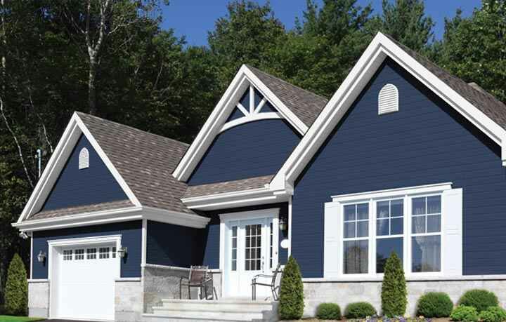 a blue house with white trim on the front and side windows, two car garage doors, and steps leading up to it