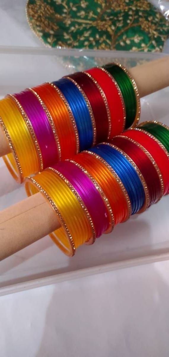 several different colored bangles sitting on top of each other in front of a mirror