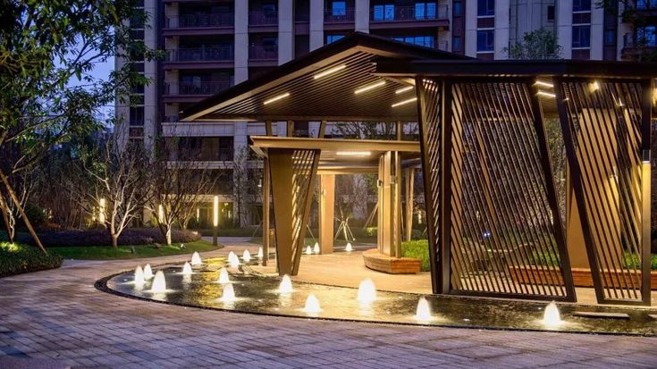 an open air pavilion with water fountains in the center and lights on it's sides