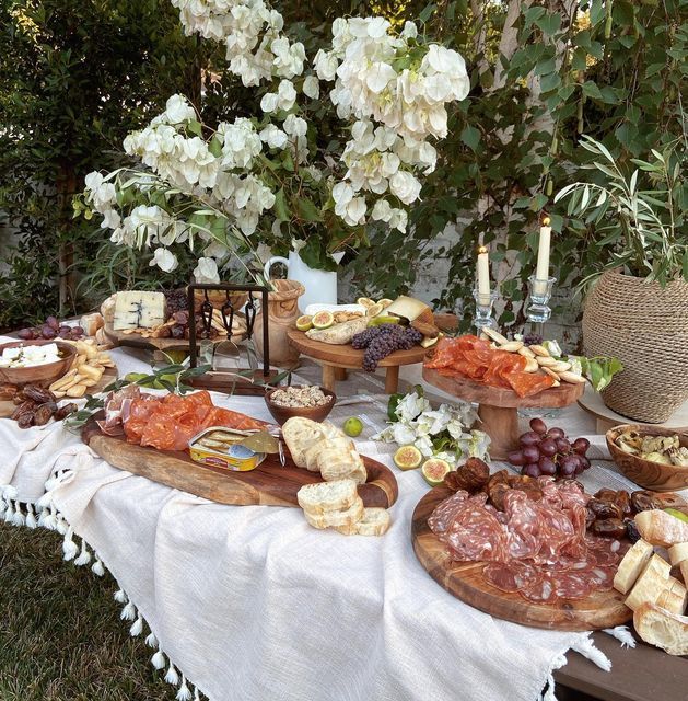 a table topped with lots of different types of cheeses and meats on wooden platters