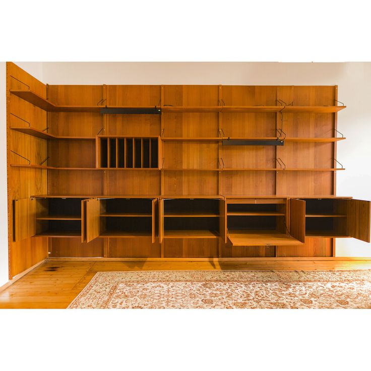 an empty room with wooden shelves and rugs on the floor in front of it