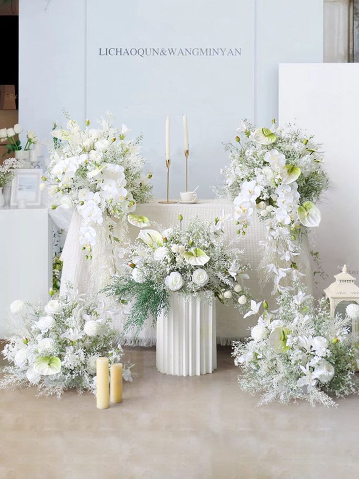 white flowers and greenery are arranged in front of the altar