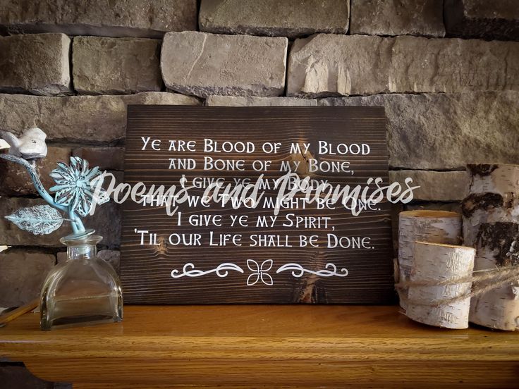 a wooden sign sitting on top of a table next to a vase filled with flowers