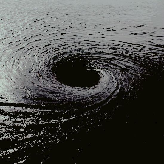 a black and white photo of water with a hole in the middle that looks like it is floating