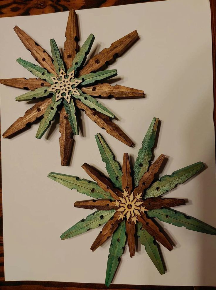 two wooden snowflakes are on a white paper